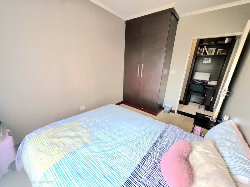 A bedroom featuring a built-in wardrobe and coving, with an adjacent small study or office nook visible through the doorway.