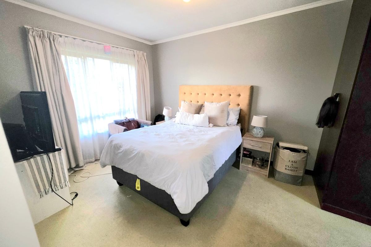 A functional bedroom featuring neutral wall tones, carpeted flooring, and a built-in wardrobe, offering a comfortable and practical living space.
