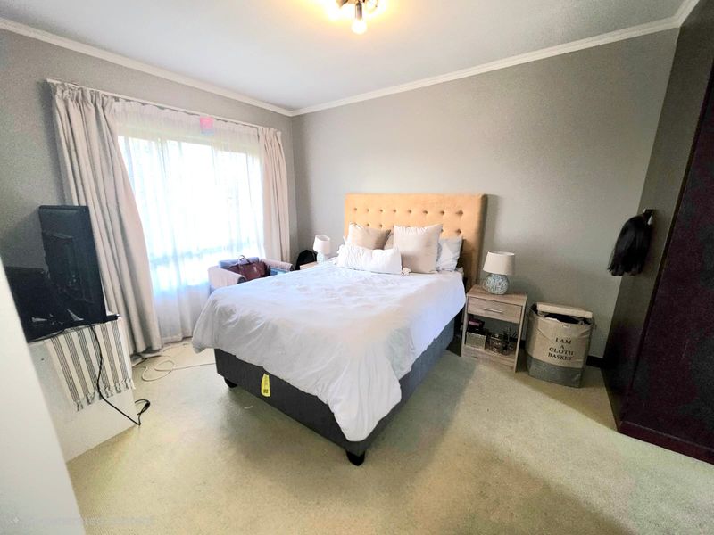 A functional bedroom featuring neutral wall tones, carpeted flooring, and a built-in wardrobe, offering a comfortable and practical living space.