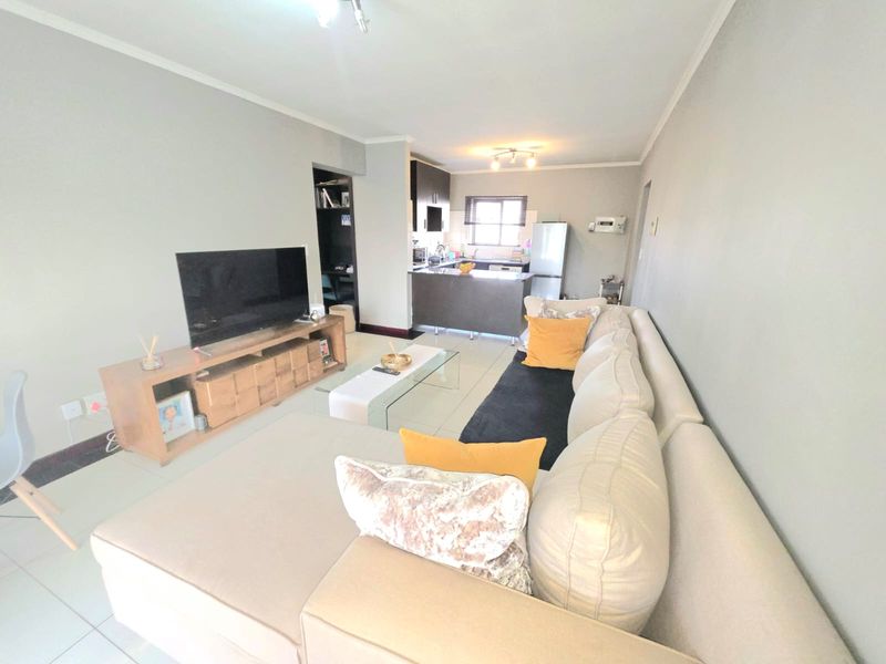 An open-plan living area featuring tiled flooring and a functional kitchen with built-in cabinetry and a breakfast island.