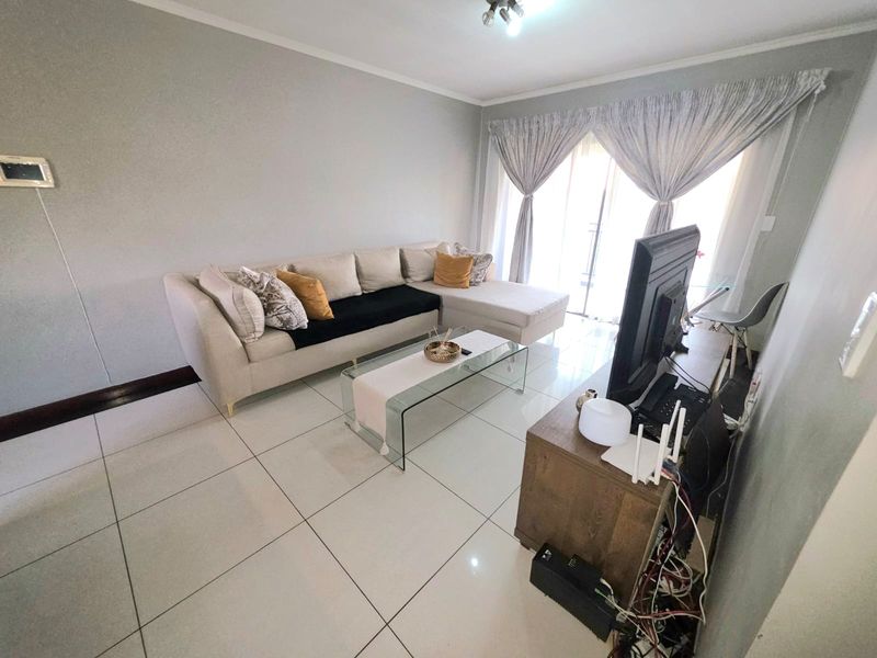 A bright living room featuring large format floor tiles and a sliding glass door providing access to the exterior.