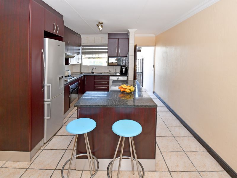 Functional kitchen featuring dark wood cabinetry, granite countertops, a central island, and tiled flooring, providing a practical workspace with direct access to the exterior.