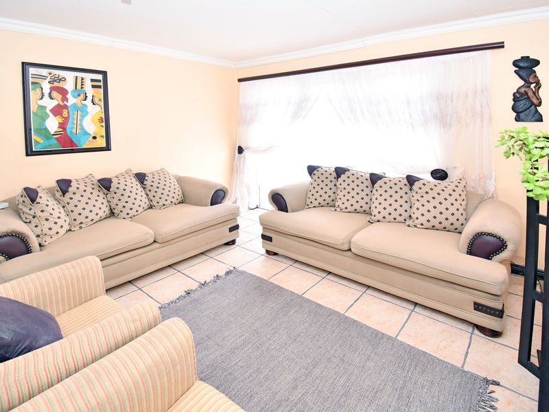 A comfortable living room featuring tiled flooring, coved ceilings, and a large sliding glass door that provides natural light.