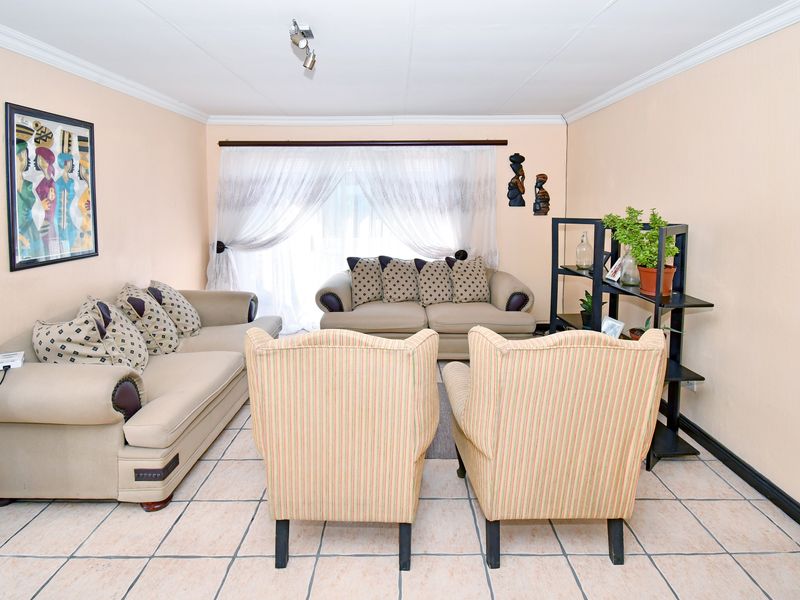 A living room featuring ceramic tile flooring, ceiling coving, and track lighting, providing a functional space for relaxation.