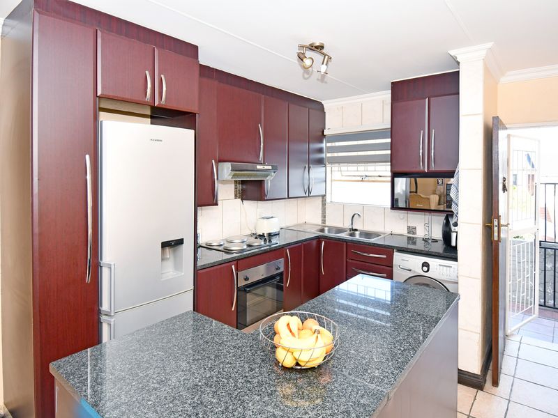 Functional kitchen featuring dark wood cabinetry, granite countertops, a central island, and built-in appliances, with direct access to an outdoor patio area.