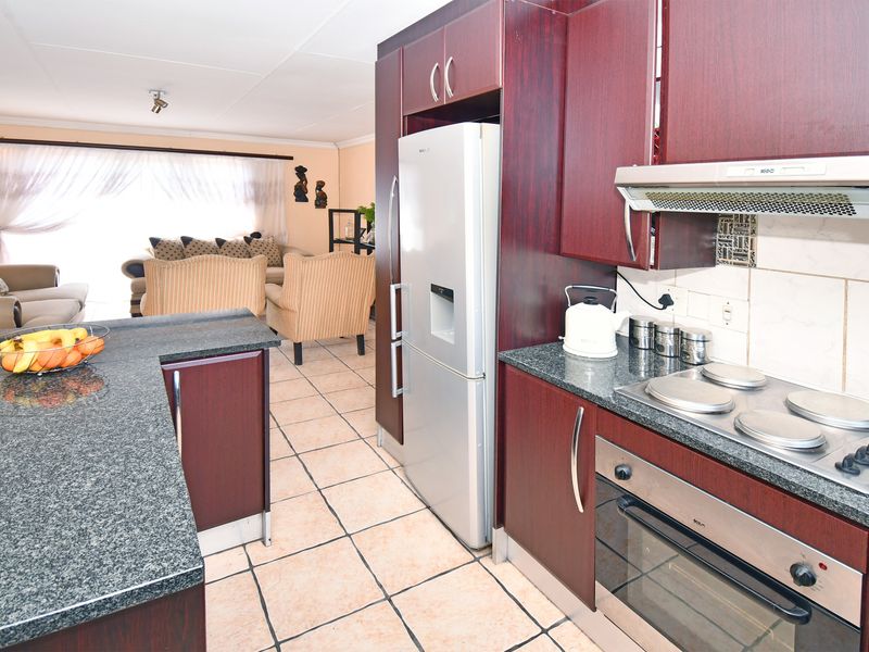Open-plan kitchen and living area featuring dark wood cabinetry, granite countertops, built-in appliances, and tiled flooring throughout.