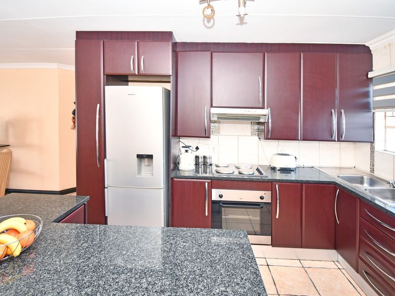 A functional kitchen featuring dark wood cabinetry, granite countertops, built-in oven, electric hob, and a double bowl stainless steel sink.