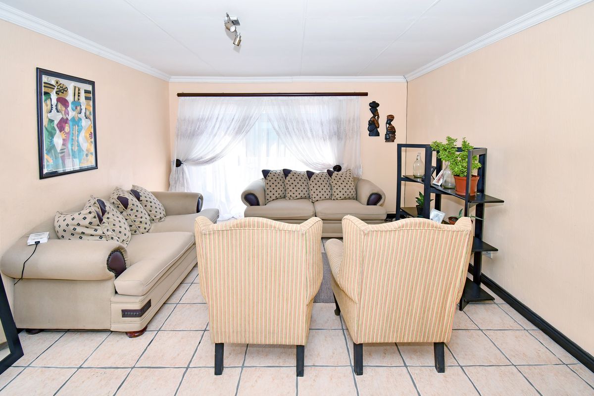 A living room featuring ceramic tile flooring, ceiling coving, and track lighting, providing a functional space for relaxation.