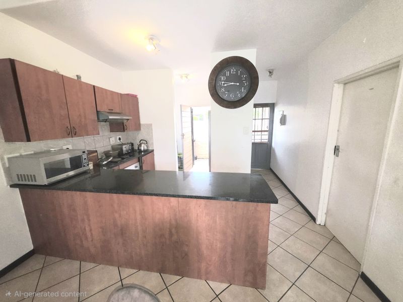 Functional kitchen featuring laminate cabinetry, granite countertops, and tiled flooring, with an open-plan layout leading to an exterior entrance.