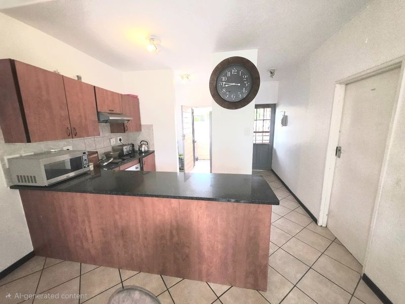 Kitchen featuring laminate cabinetry, granite countertops, and ceramic floor tiles, with an open-plan layout leading to an exterior security door.