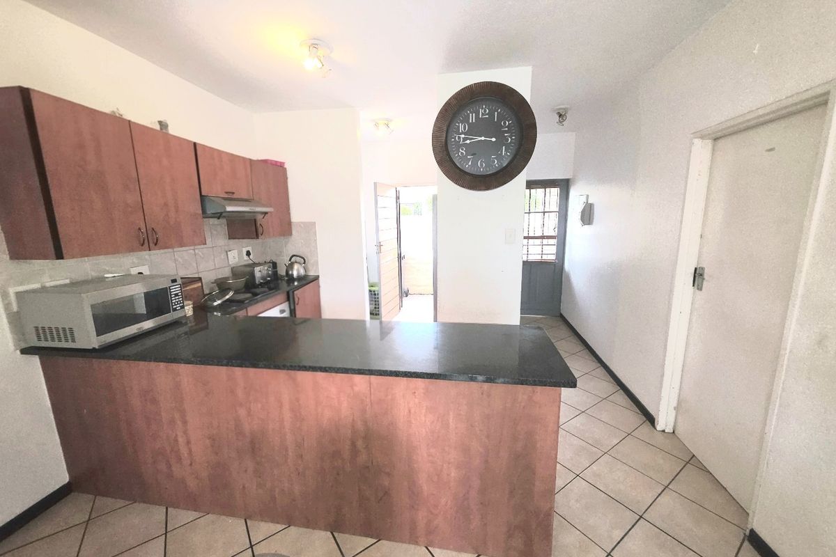 Kitchen featuring laminate cabinetry, granite countertops, and ceramic floor tiles, with an open-plan layout leading to an exterior security door.