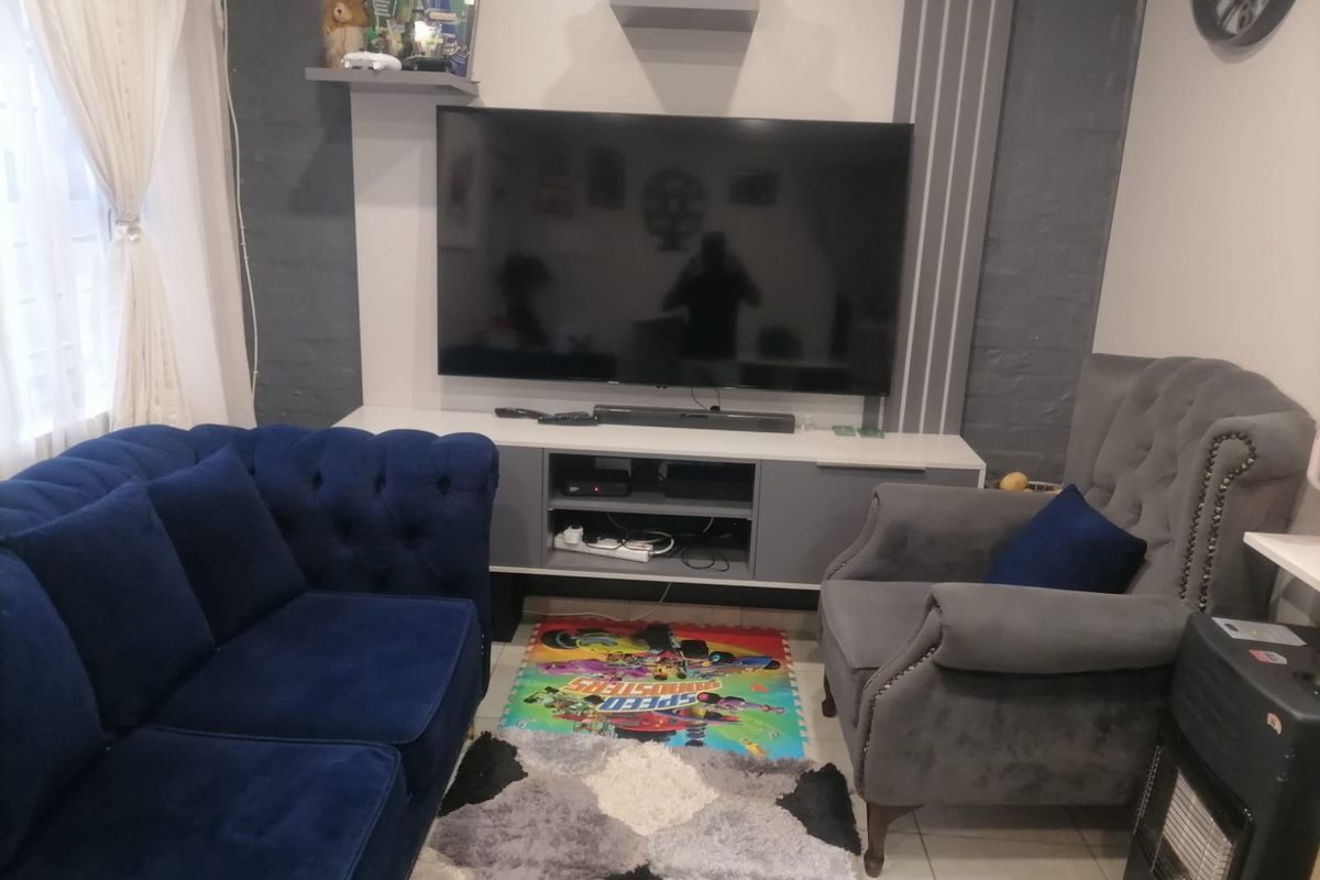 A cozy living room featuring a built-in media console, decorative wall paneling, and tiled flooring, providing a functional space for entertainment.