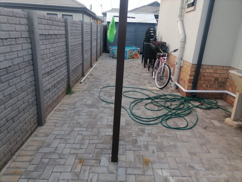 A paved rear courtyard area featuring a precast concrete boundary wall and external drainage infrastructure.