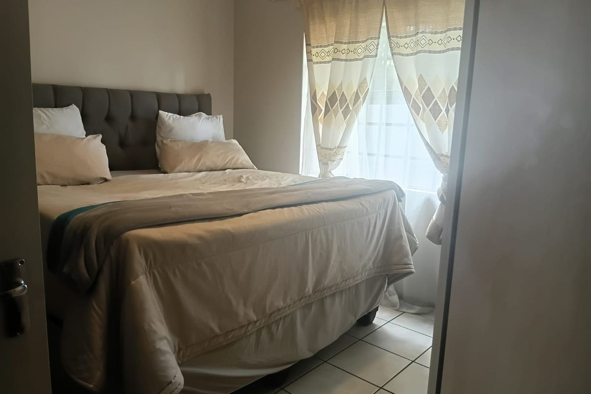 A bedroom featuring tiled flooring and a window with a curtain rod, providing a functional and neutral space.