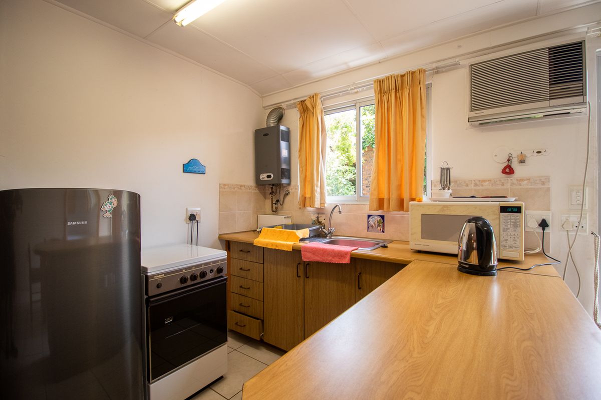 A functional kitchen featuring laminate countertops, built-in cabinetry, a gas stove, and a wall-mounted gas geyser.