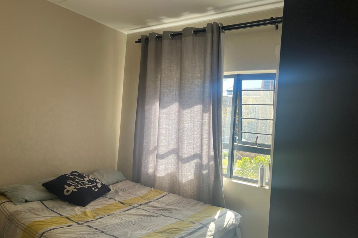 A bedroom featuring a window with security bars and curtain rod.