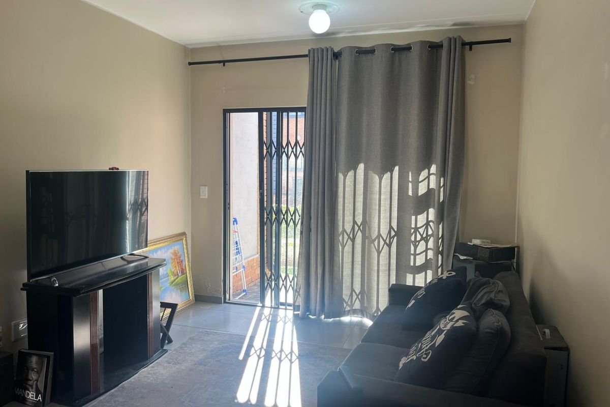 A living room featuring tiled flooring and a security gate leading to an outdoor area, providing natural light and access.
