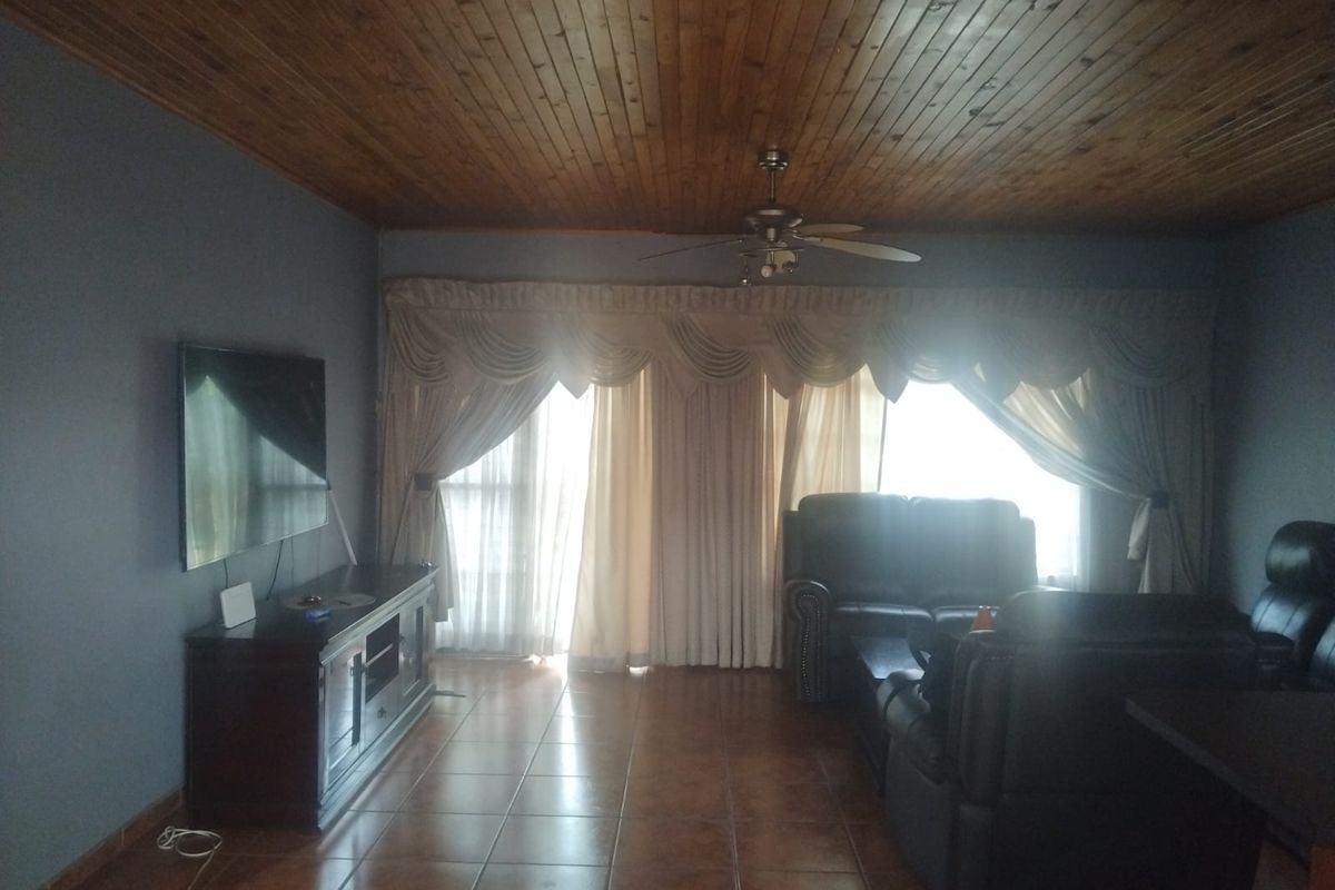 A living room featuring tiled flooring and a timber-clad ceiling with a central ceiling fan.