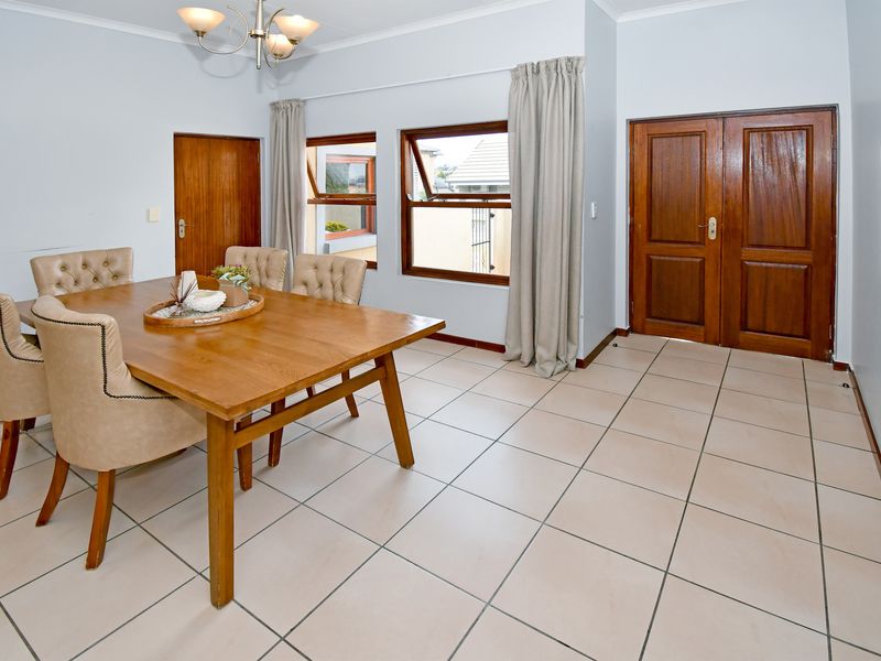 A dining room featuring tiled flooring, timber doors, and top-hung windows, providing a functional space for meals.