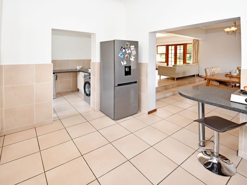 Open-plan kitchen area featuring granite countertops, a breakfast bar, and an adjoining scullery, flowing into the dining and living spaces.