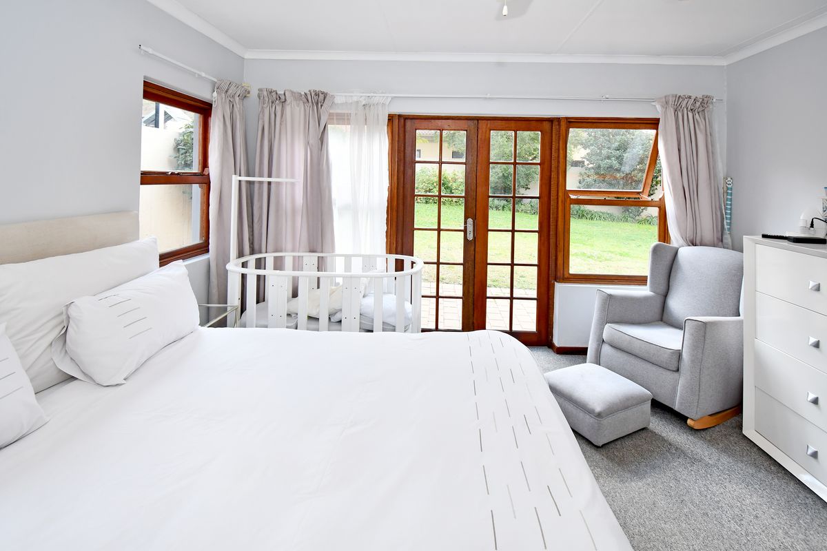 A bright bedroom featuring timber-framed french doors that open directly onto the rear garden, providing natural light and easy outdoor access.