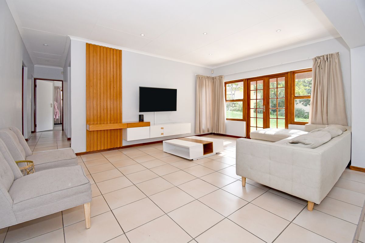 Spacious living room featuring tiled flooring, recessed lighting, and timber-framed glass doors providing access to the garden.