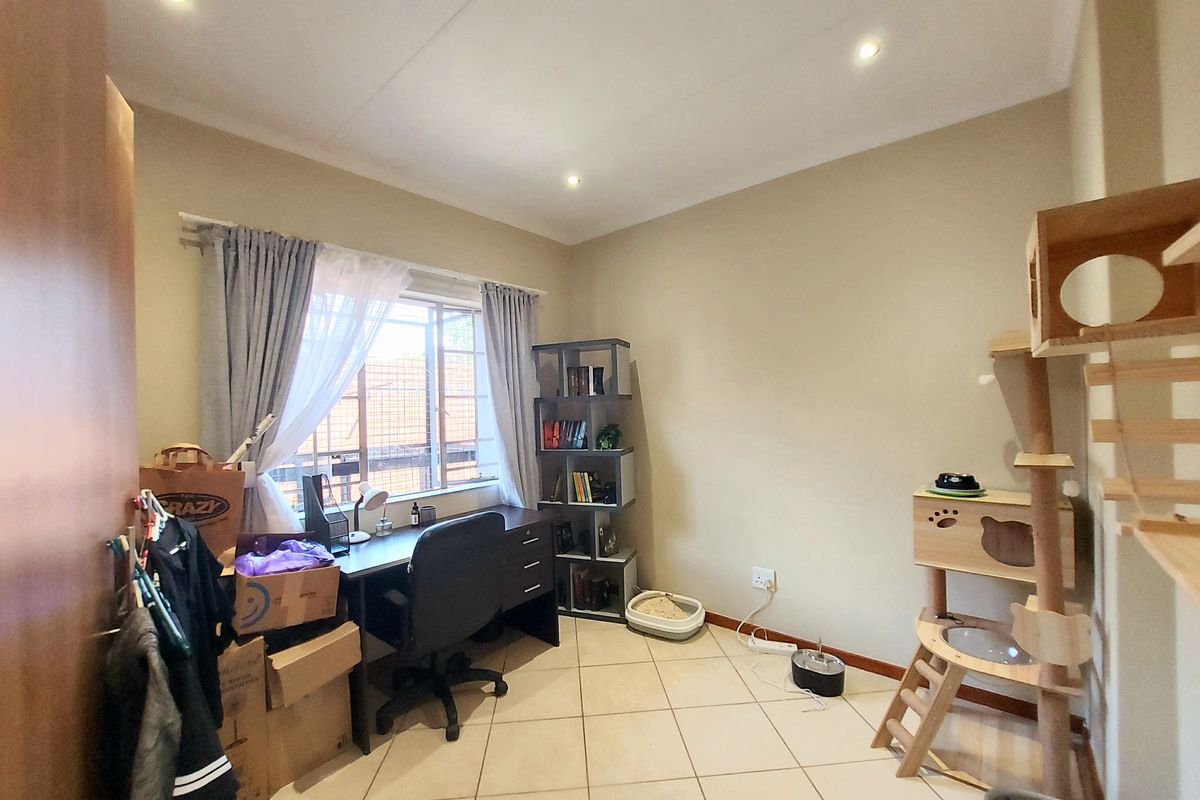 A functional bedroom featuring tiled flooring, recessed ceiling lighting, and a window with security bars.