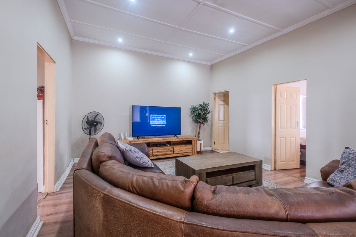 A spacious living room featuring laminate flooring, recessed downlights, and a panelled ceiling, providing a comfortable and functional family area.