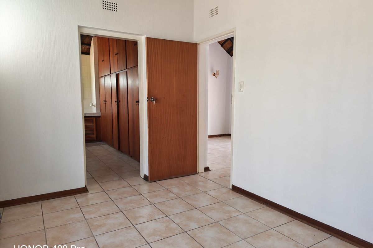 An interior view of a room featuring tiled flooring, wooden doors, and built-in cabinetry visible through the doorway.