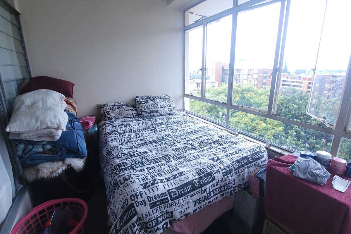 A bedroom featuring large windows that provide ample natural light and an elevated view of the surrounding neighborhood.
