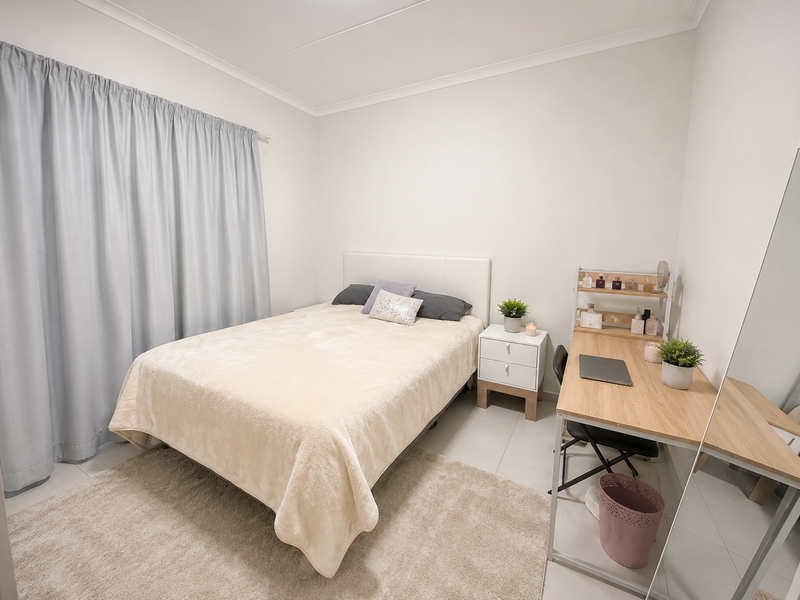 A well-maintained bedroom featuring neutral wall finishes, tiled flooring, and cove cornicing, providing a clean and functional living space.