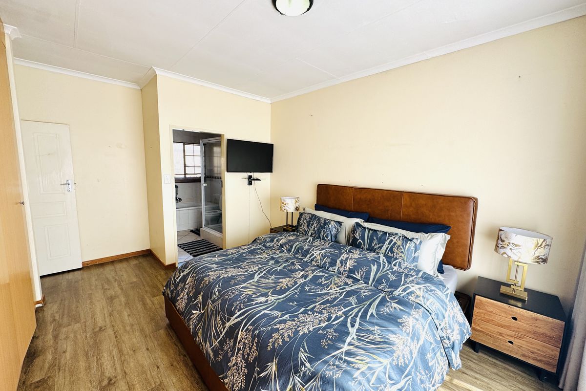 A well-lit bedroom featuring laminate flooring, built-in storage, and direct access to an en-suite bathroom.