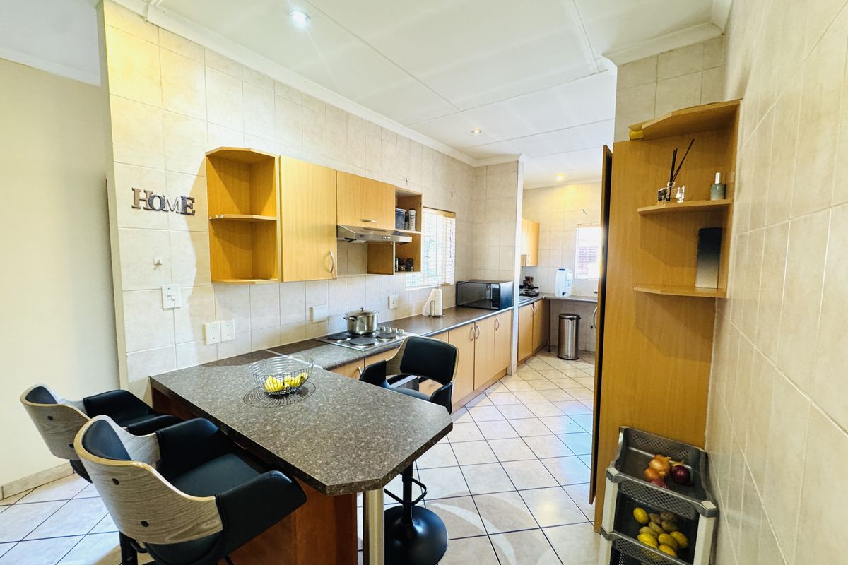 A functional kitchen featuring built-in wooden cabinetry, laminate countertops, a breakfast nook, and tiled finishes throughout.