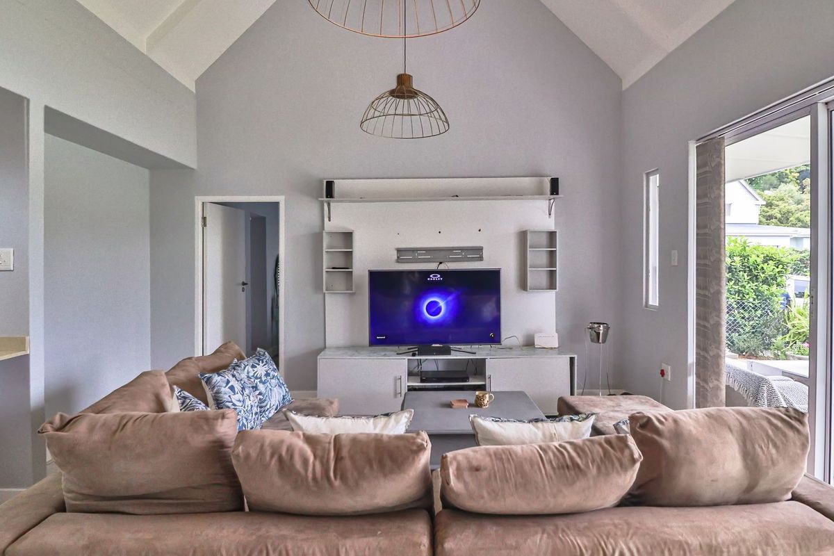 Spacious living room featuring a high vaulted ceiling, built-in media cabinetry, and large sliding glass doors providing seamless access to the outdoor patio area.