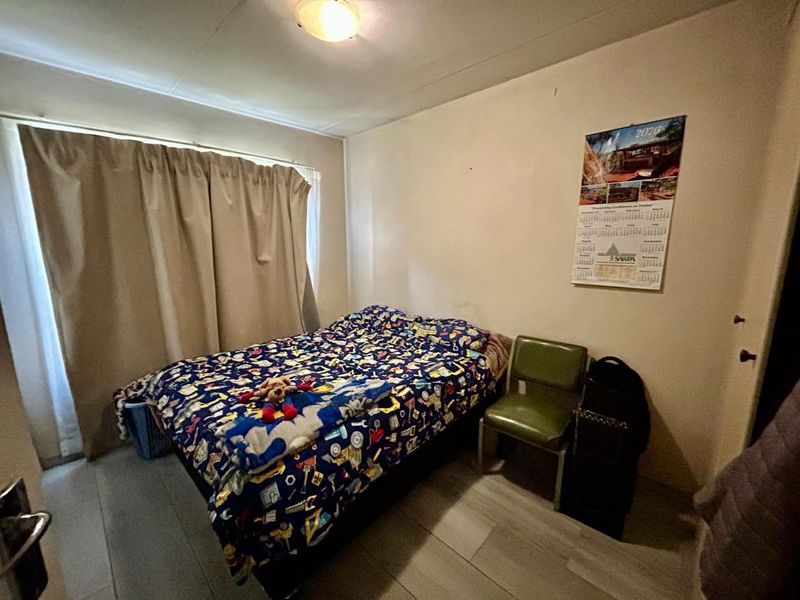 A standard bedroom featuring tiled flooring and a window with curtain tracks.