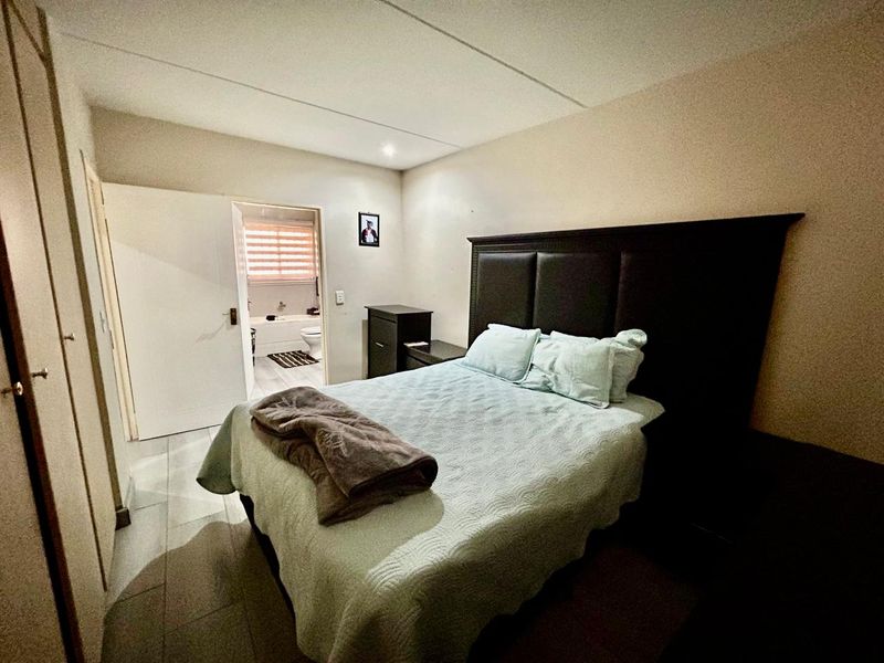A bedroom featuring built-in cupboards and an en-suite bathroom with tiled flooring throughout.