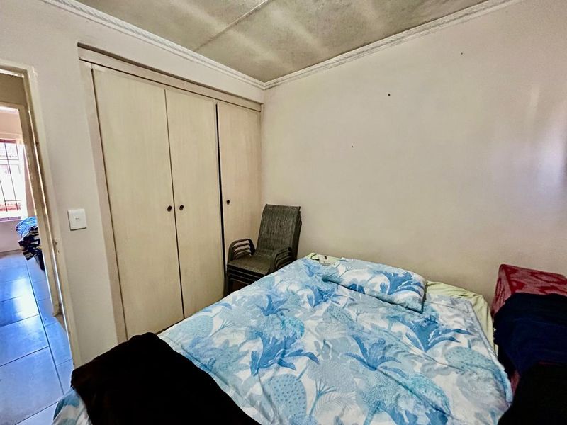 A bedroom featuring built-in wooden cupboards and a ceiling with visible signs of wear and staining.