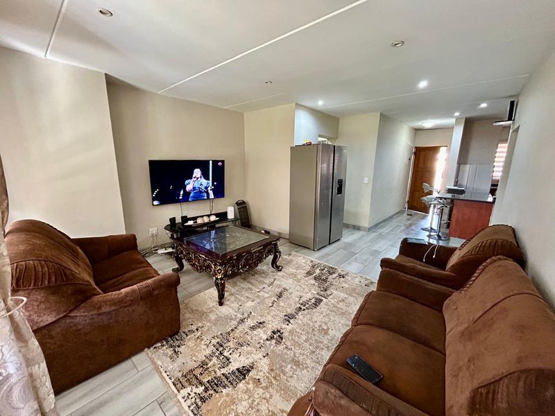 Open-plan living area featuring tiled flooring, recessed downlighting, and a seamless transition into the kitchen space.