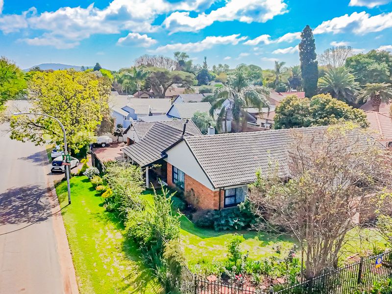 Aerial view of a residential property featuring a tiled roof, brick exterior, and established garden in a suburban street setting.