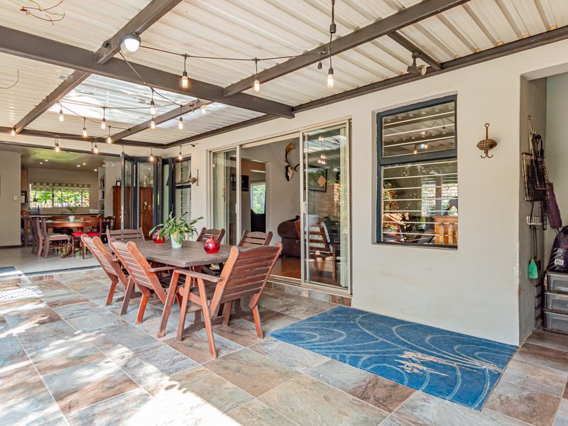 Spacious covered patio featuring tiled flooring, metal roof structure, and large sliding glass doors providing seamless access to the interior living areas.