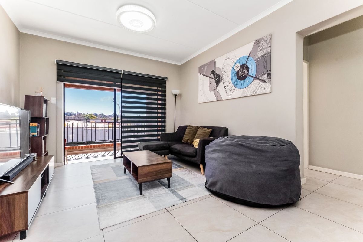 A bright living room featuring tiled flooring, a modern ceiling light, and sliding glass doors that open onto a private balcony.