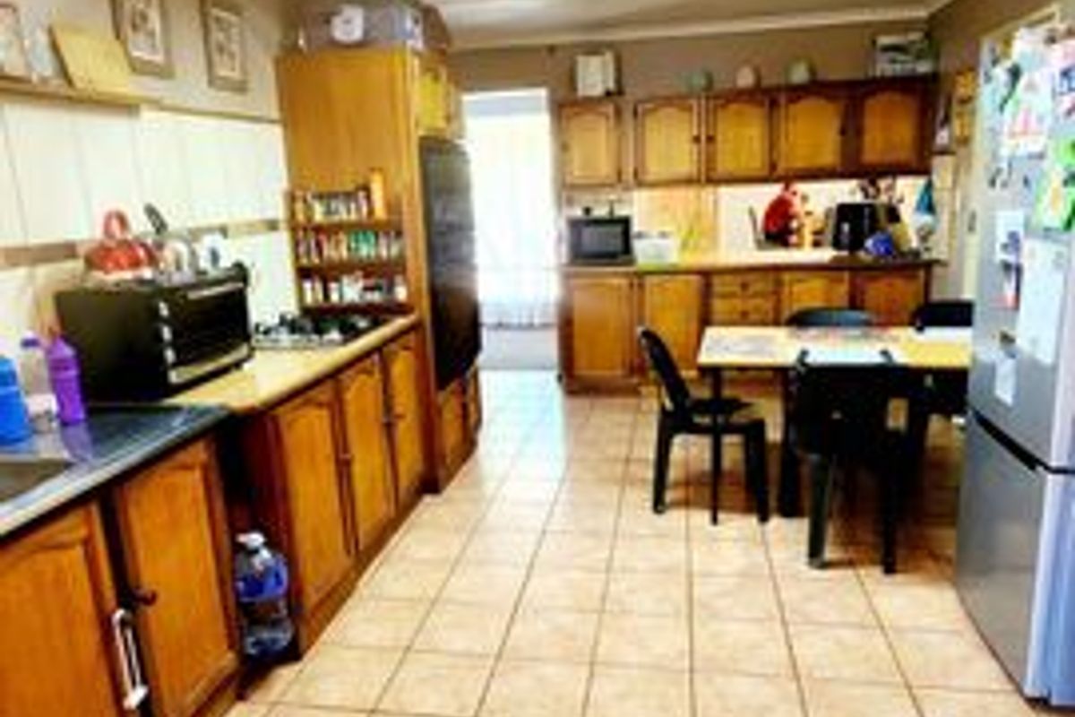 A functional kitchen featuring extensive wooden cabinetry, laminate countertops, and ceramic tile flooring, offering a traditional layout with ample storage space.