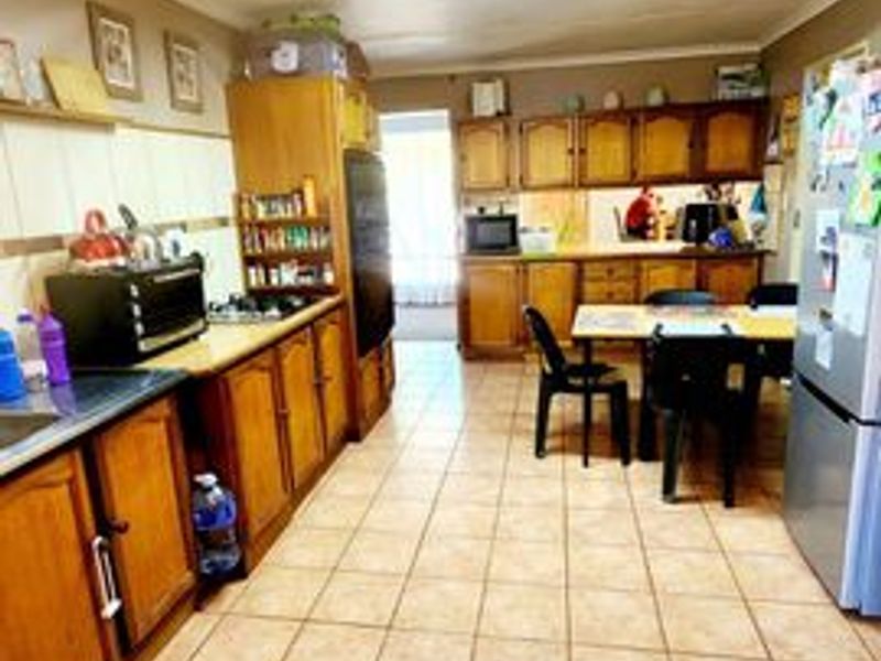A functional kitchen featuring extensive wooden cabinetry, laminate countertops, and ceramic tile flooring, offering a traditional layout with ample storage space.