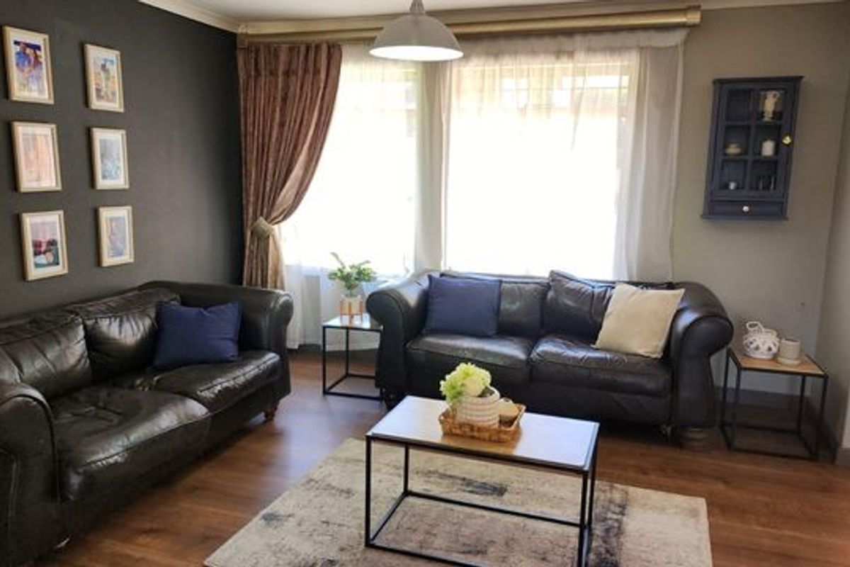 A comfortable living room featuring laminate flooring, coving, and a neutral color palette, creating a warm and inviting space for relaxation.