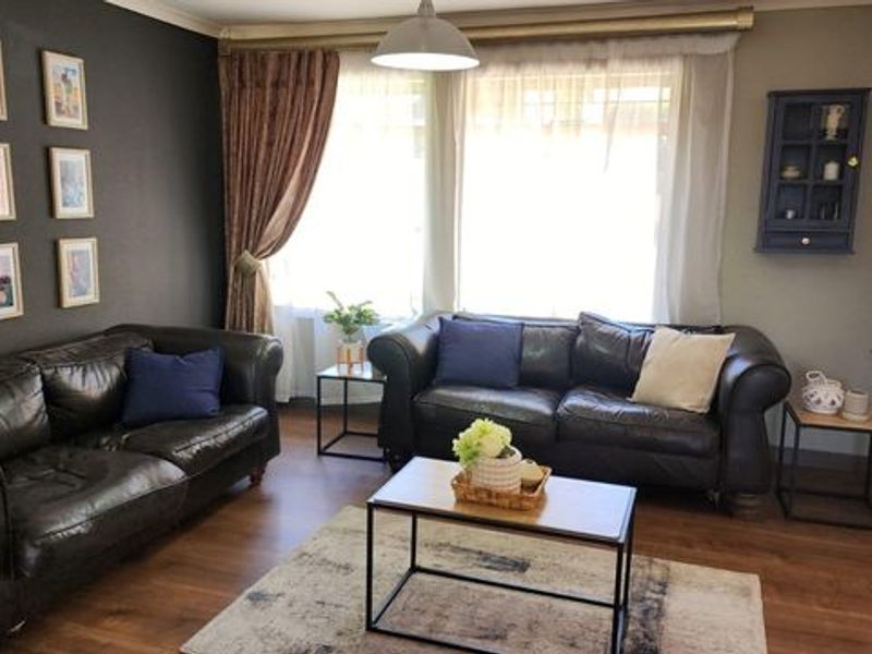 A comfortable living room featuring laminate flooring, coving, and a neutral color palette, creating a warm and inviting space for relaxation.