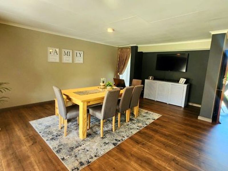 Spacious dining area featuring durable laminate flooring, neutral wall tones, and direct access to the exterior through a secure entrance.