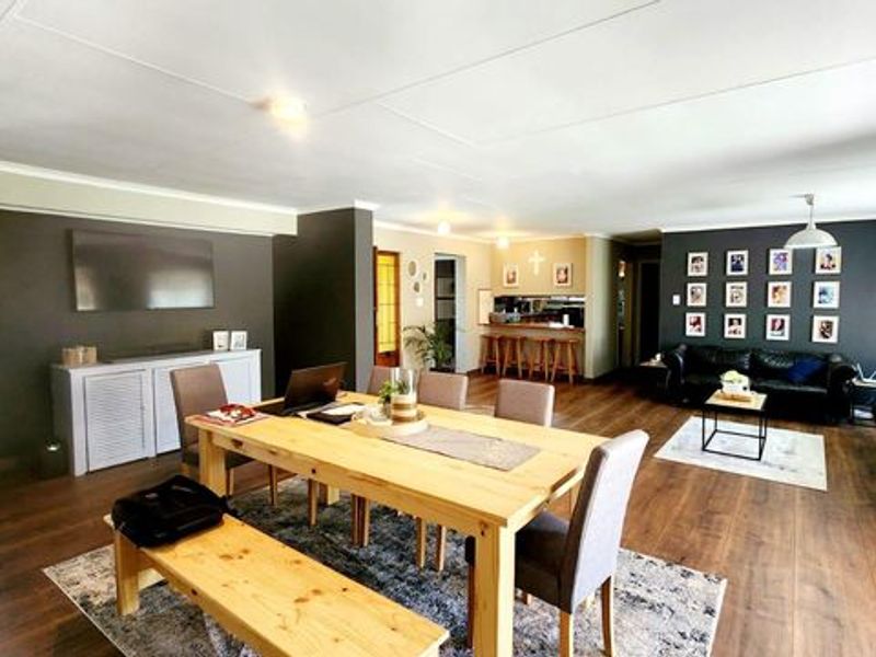 Spacious open-plan living and dining area featuring dark accent walls, laminate flooring, and a convenient built-in breakfast bar.