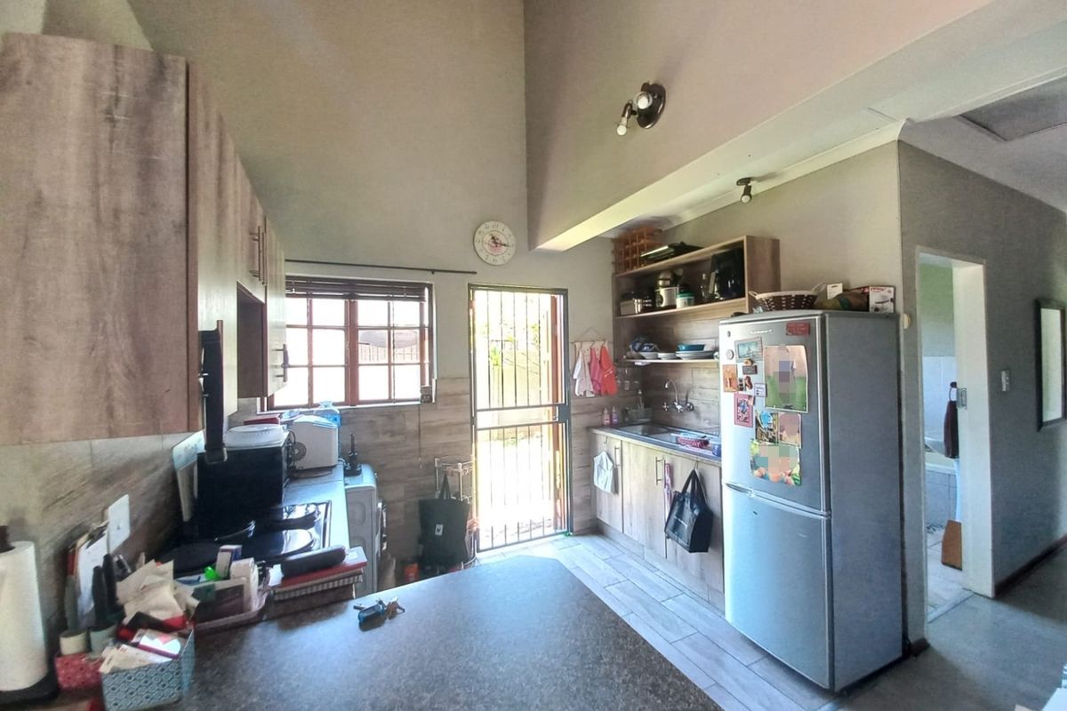 A functional kitchen featuring built-in cabinetry, laminate countertops, tiled flooring, and a vaulted ceiling with direct access to the exterior.
