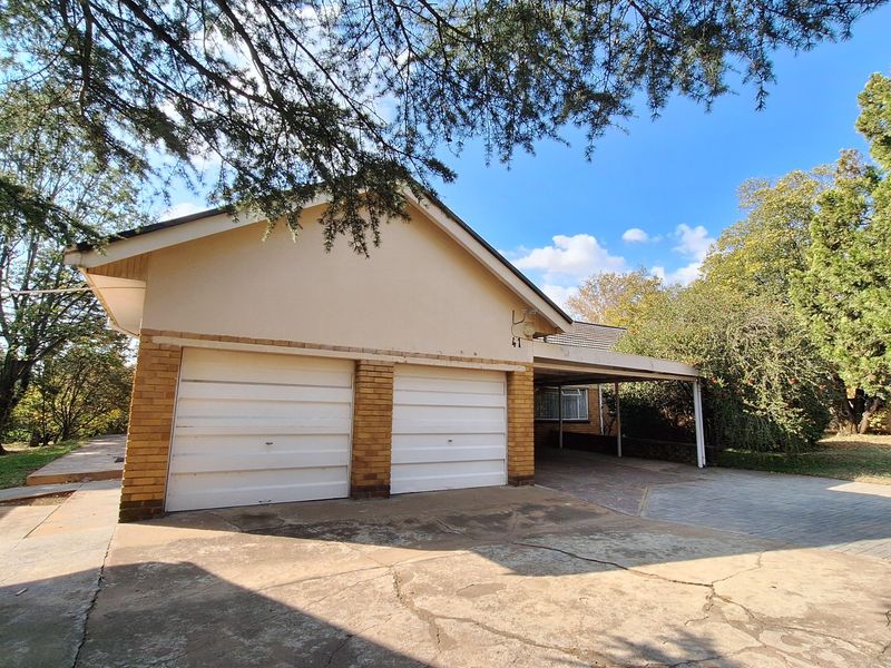 Front exterior view featuring a double garage, attached carport, and a paved driveway area.