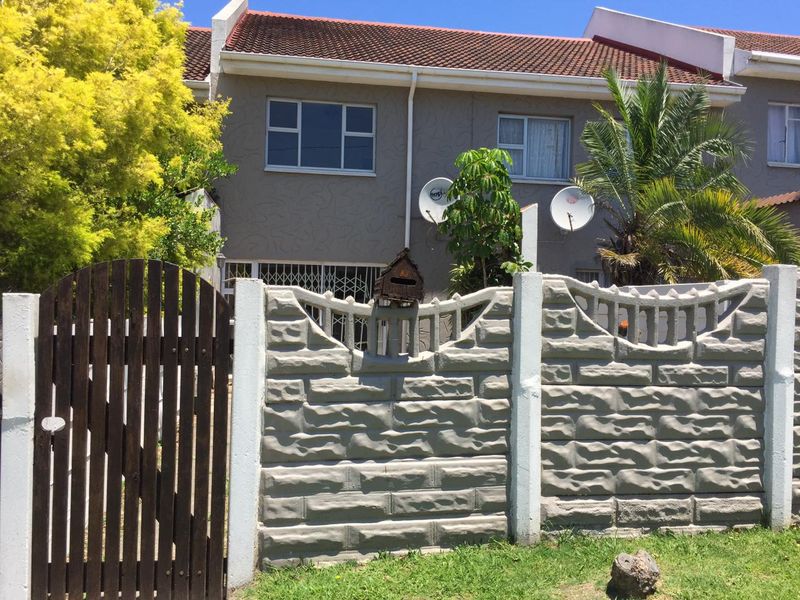 Front exterior view of a two-story apartment unit featuring a precast concrete boundary wall, timber gate, and tiled roof.